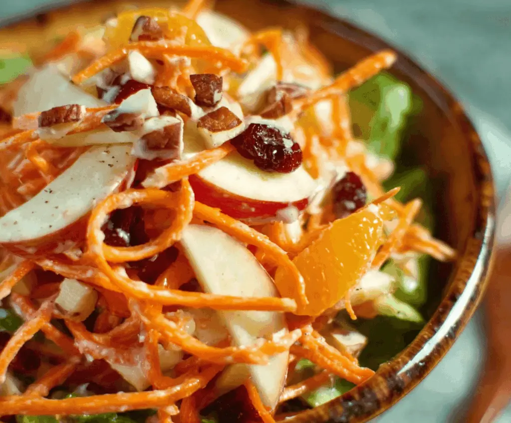 Fresh carrot and apple salad with sliced carrots and crisp apple pieces, topped with chopped nuts and herbs for a healthy, colorful dish