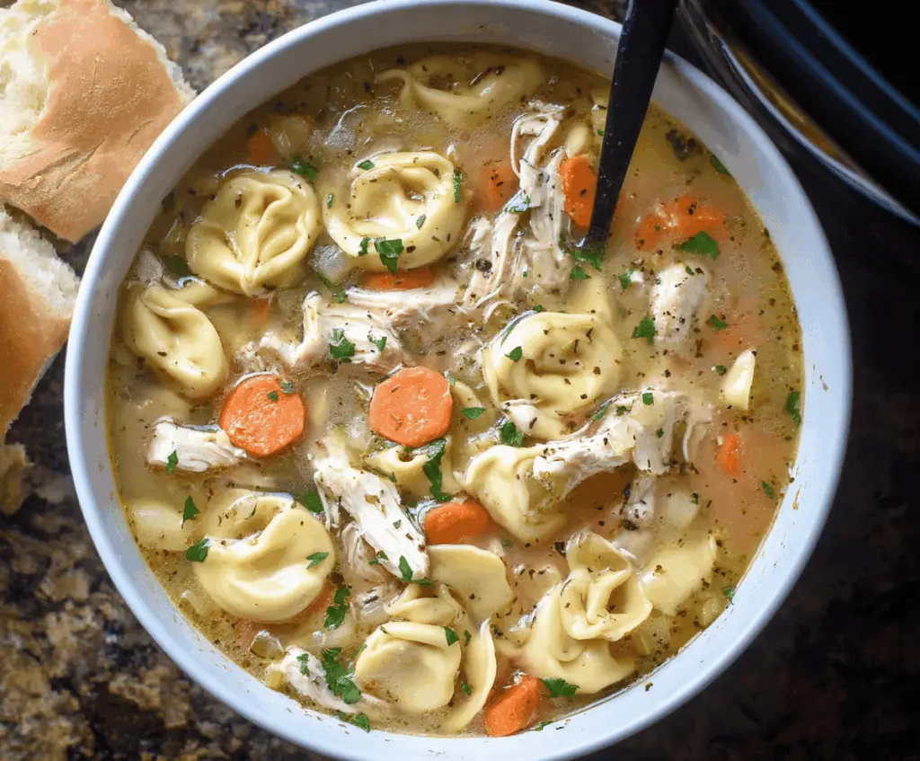 Creamy crockpot chicken tortellini soup with vegetables and herbs in a bowl, perfect for a comforting meal