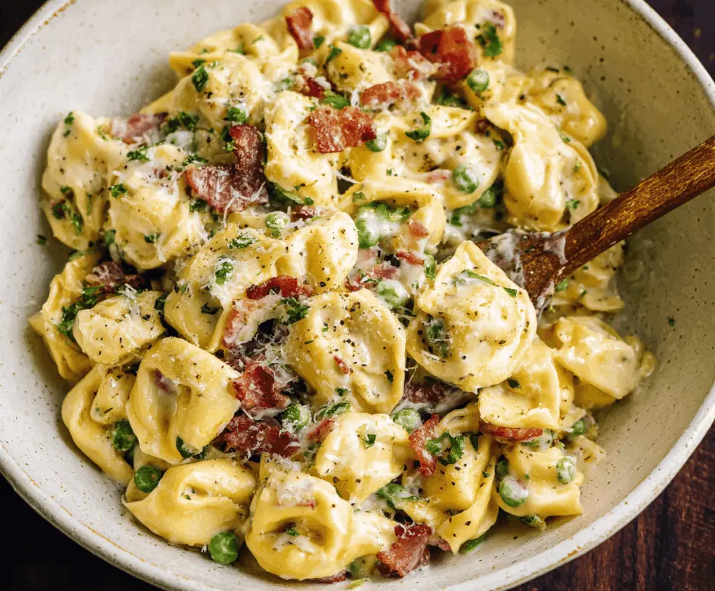 Creamy tortellini carbonara served in a bowl topped with grated cheese and fresh herbs, featuring a rich, flavorful sauce perfect for a comforting Italian meal.