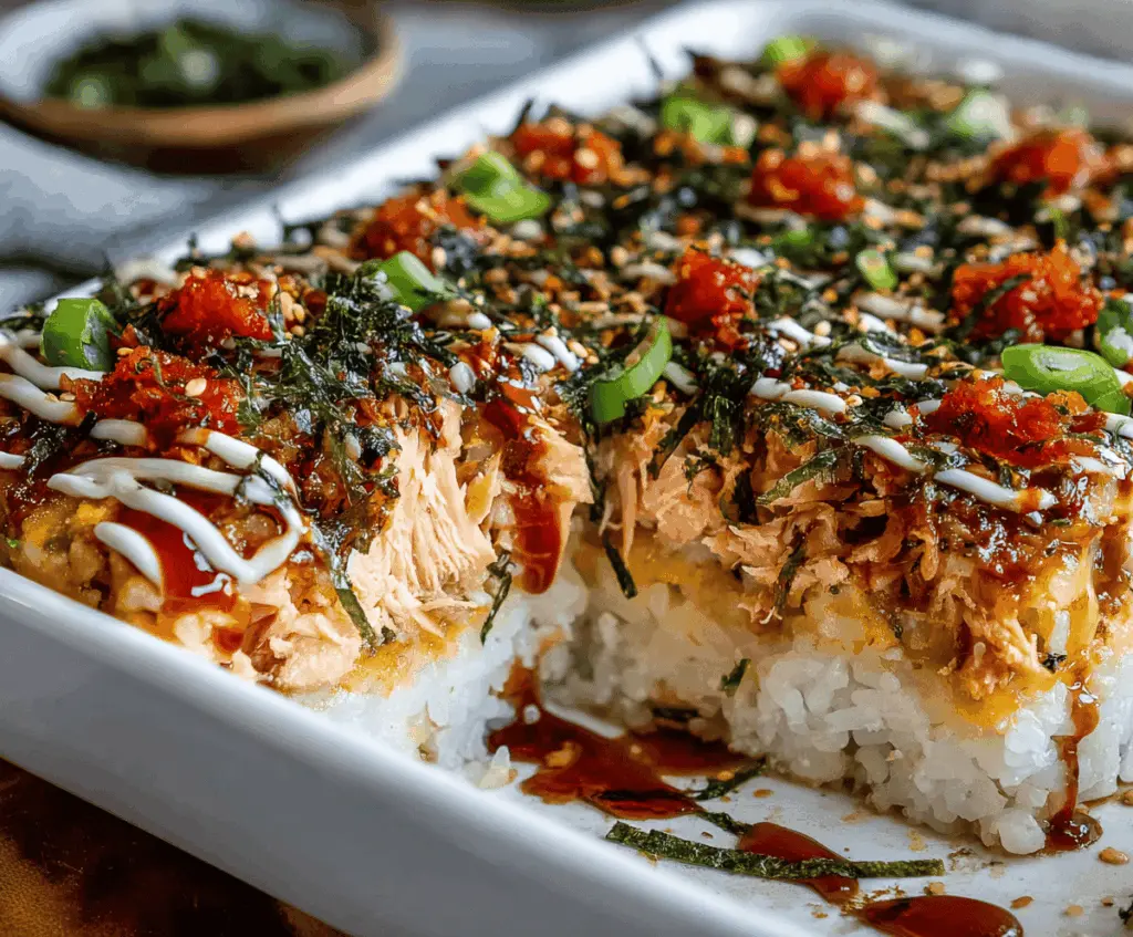 Delicious salmon sushi bake with creamy topping and fresh ingredients on a platter.