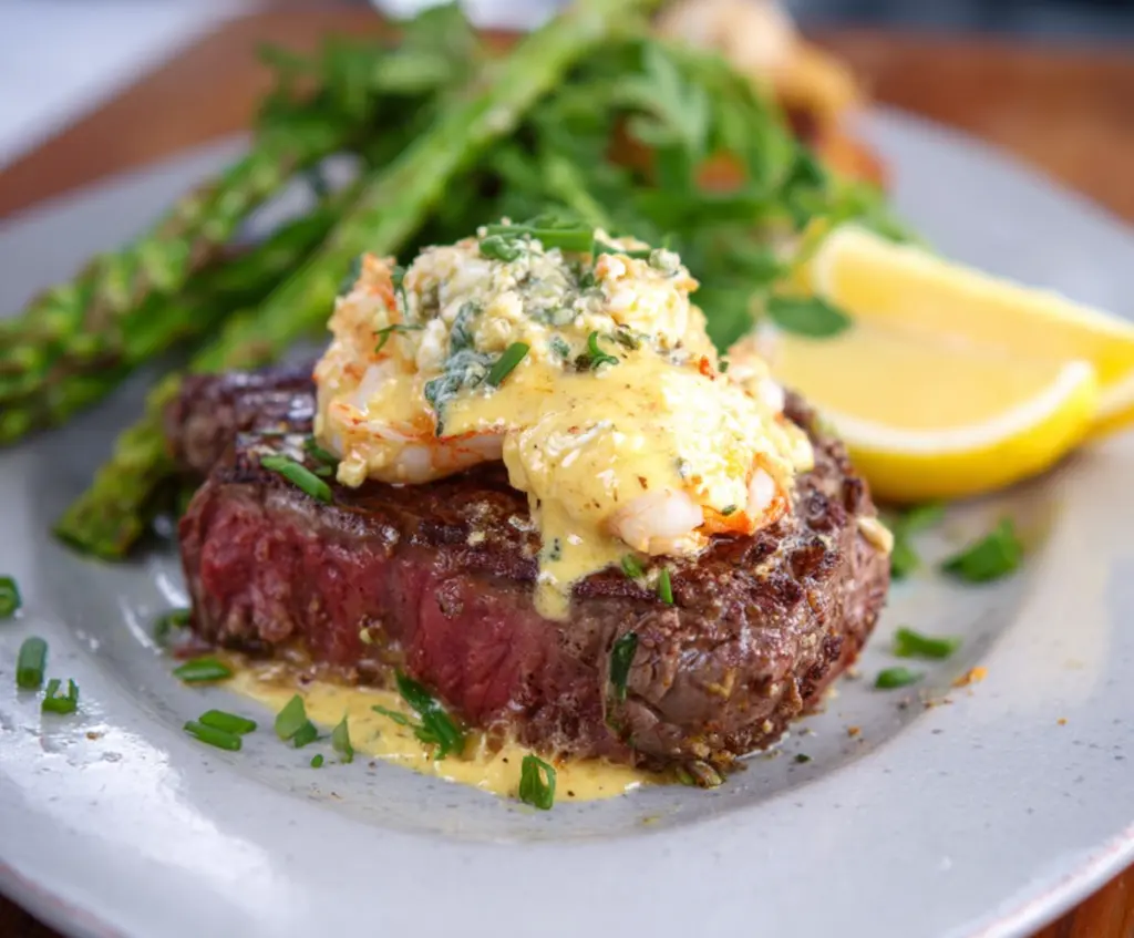 Delicious Steak Oscar featuring tender beef topped with luxurious crab meat, asparagus, and creamy hollandaise sauce.
